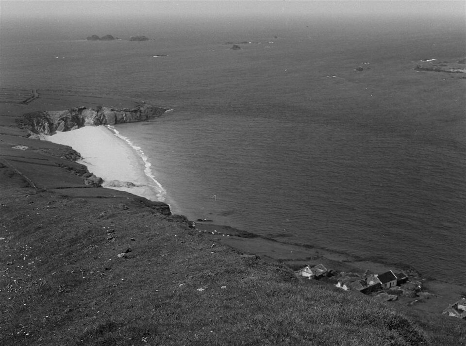 Black-and-white view of the old village and beach on Great Blasket Island, with abandoned houses on the hillside above the Atlantic.