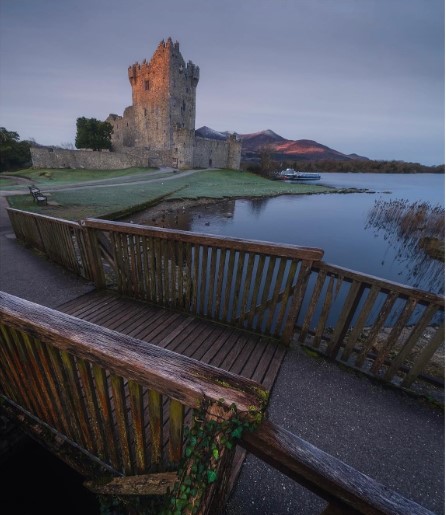 Ross Castle in Killarney at sunrise, with the last golden light catching the mountains beyond, photographed by Stephen Phelan.